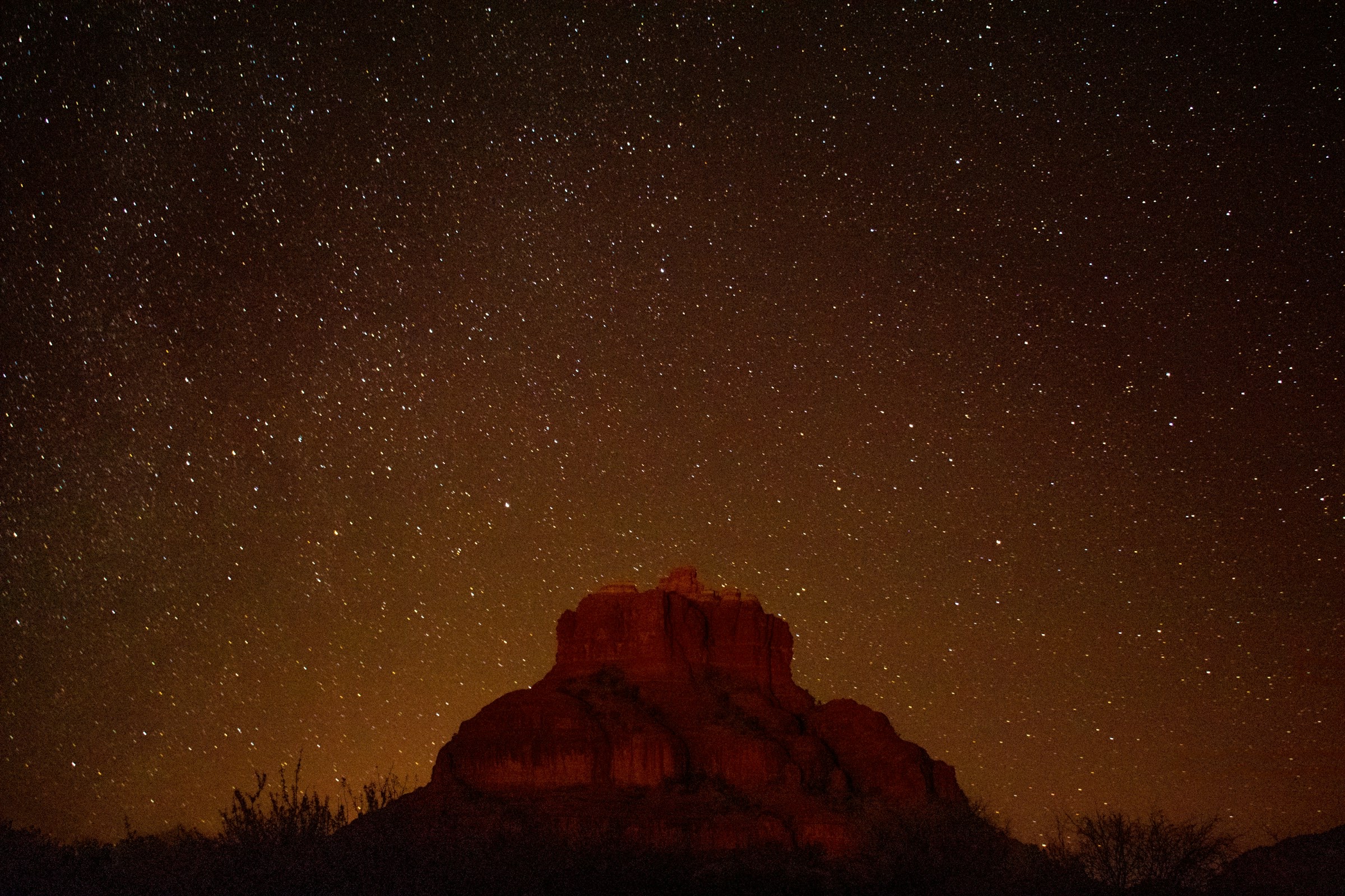Bell Rock under a starlit sky with warm horizon glow
